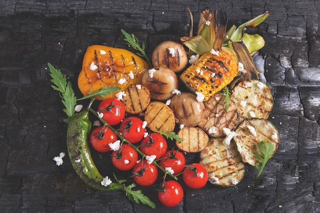 Vista ad alto angolo di pomodori con carne e verdure alla griglia su tavola