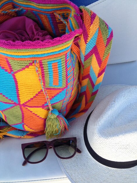 Vista ad alto angolo di una borsa wayuu e un cappello di paglia con occhiali da sole sul tavolo