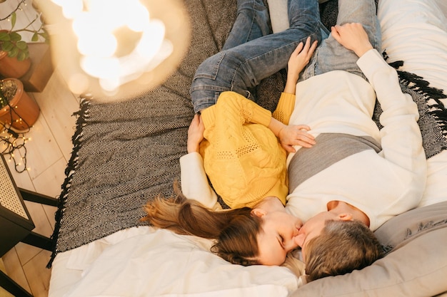 Vista ad alto angolo di una coppia che si bacia sdraiata a letto a casa