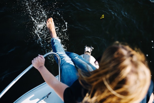Vista ad alto angolo di una donna che spruzza acqua mentre è seduta su una barca