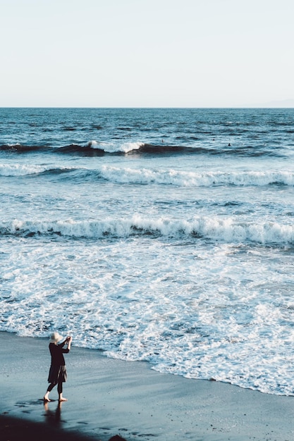 Vista ad alto angolo di una donna in piedi sulla spiaggia contro un cielo limpido