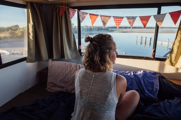 Vista ad alto angolo di una donna sdraiata sul letto vicino alla finestra