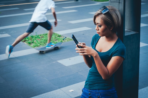 Vista ad alto angolo di una giovane donna che usa il telefono cellulare mentre si trova accanto alla colonna in città
