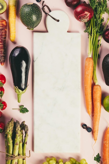 Vista ad alto angolo di verdure e frutta con tavola da taglio sul tavolo