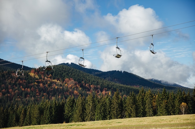 Vista ad angolo basso dell'impianto di risalita da qualche parte sulle montagne dei Carpazi con una straordinaria natura mattutina intorno. Bellezza della foresta verde e del cielo blu.