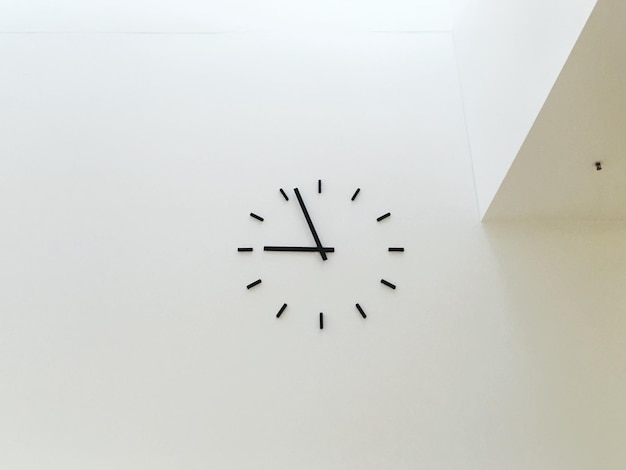 Vista ad angolo basso dell'orologio sulla parete bianca