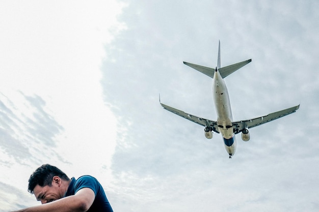 Vista ad angolo basso dell'uomo sotto l'aereo che vola contro il cielo