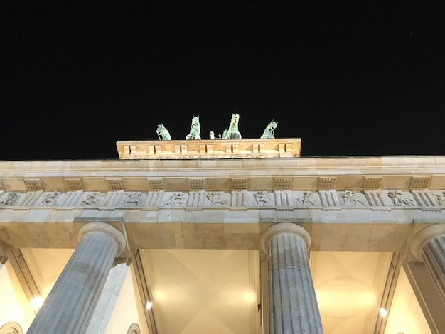 Vista ad angolo basso della Porta di Brandeburgo illuminata contro un cielo limpido di notte