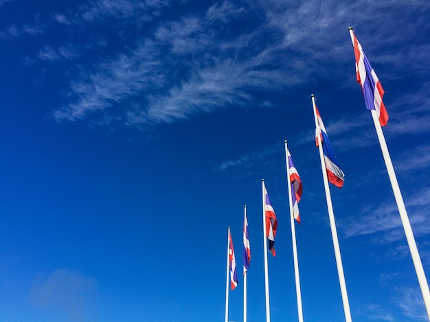 Vista ad angolo basso delle bandiere thailandesi in fila contro il cielo blu