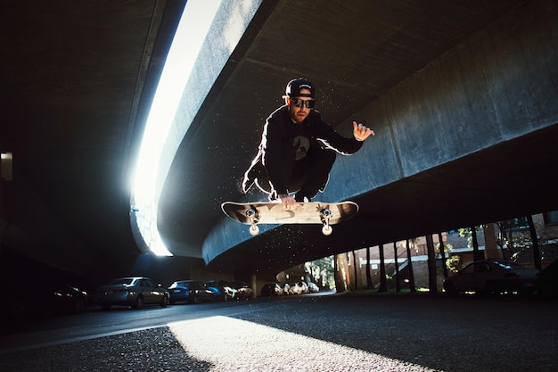 Vista ad angolo basso di un uomo che salta su uno skateboard