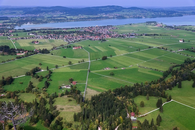 Vista aerea dal drone della valle dei campi del lago del villaggio ai piedi delle montagne alpine in Baviera, Germania