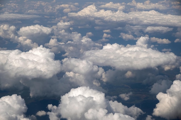 Vista aerea dal finestrino dell'aereo di nuvole bianche gonfie in una luminosa giornata di sole.