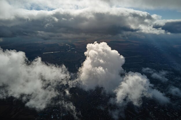 Vista aerea dal finestrino dell'aeroplano ad alta quota della città lontana ricoperta di nubi cumuliformi bianche e gonfie