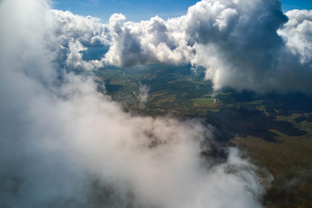 Vista aerea dal finestrino dell'aeroplano ad alta quota della terra coperta da nubi cumuliformi gonfie che si formano prima del temporale