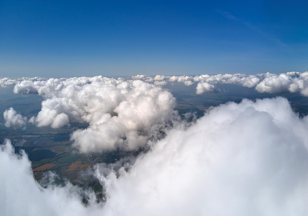 Vista aerea dal finestrino dell'aeroplano ad alta quota della terra ricoperta di nubi cumuliformi bianche e gonfie.