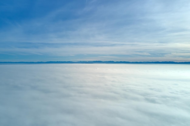 Vista aerea dall'alta quota della terra ricoperta di nubi bianche gonfie in una giornata di sole