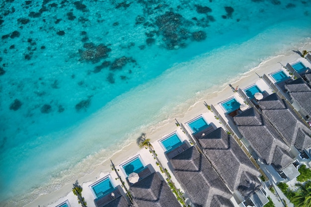 Vista aerea dall'alto dei bungalow delle ville con piscina nella spiaggia tropicale paradisiaca del resort delle Maldive Blues incredibili
