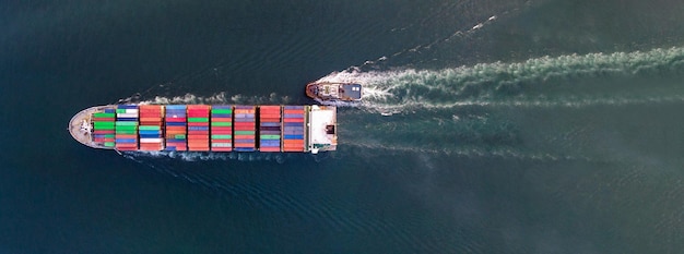 Vista aerea dall'alto della nave da carico che trasporta container e funziona con rimorchiatore per l'esportazione di merci dal porto del cantiere di merci al trasporto di merci su ordinazione dell'oceano via nave