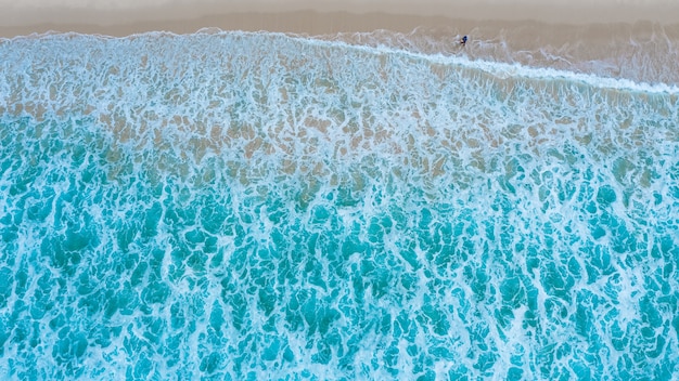 Vista aerea dall'alto della spiaggia sabbiosa con turisti in viaggio nella bellissima onda del mare