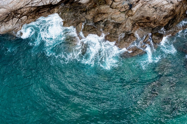 Vista aerea dall'alto delle onde del mare che colpiscono le rocce fotografano il drone di punto di vista