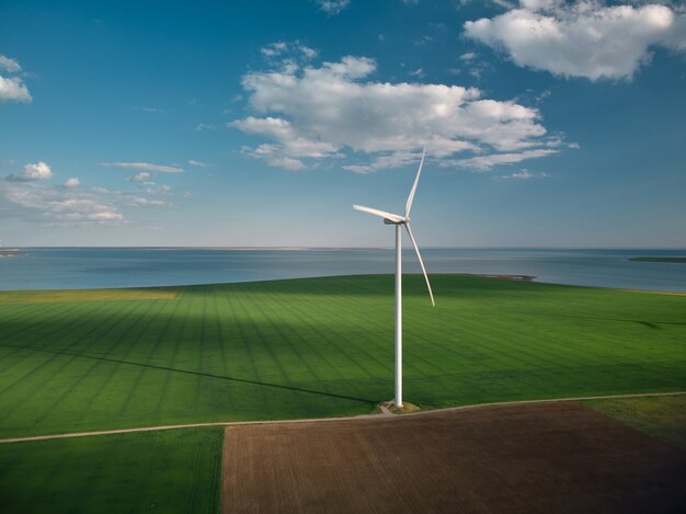 Vista aerea dall'alto delle turbine eoliche e del campo agricolo vicino al mare al tramonto