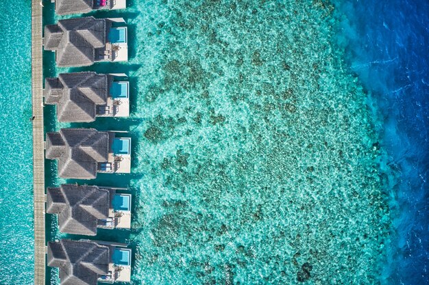 Vista aerea dall'alto di ville con piscina, bungalow nella spiaggia tropicale del paradiso delle Maldive. Incredibile turchese blu