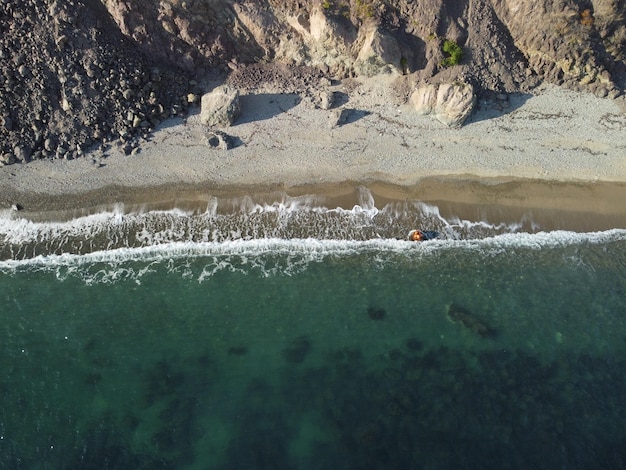 Vista aerea dall'alto sul mare azzurro calmo e sulle sponde rocciose vulcaniche piccole onde sulla superficie dell'acqua in