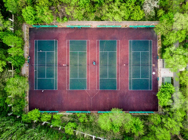 Vista aerea dall'alto verso il basso dei campi da tennis nella foresta tra alberi