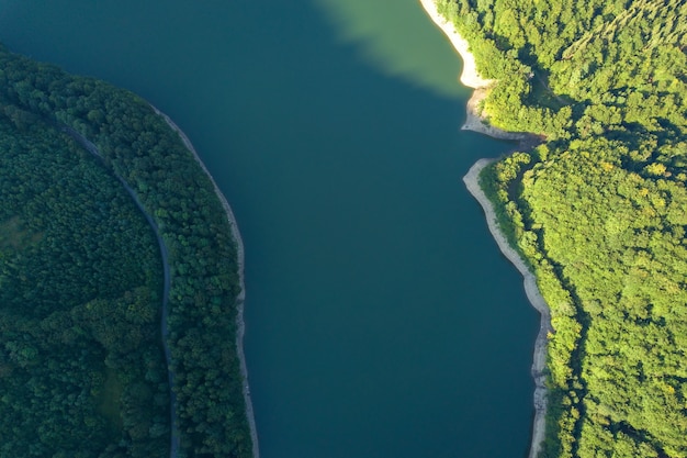 Vista aerea dall'alto verso il basso del grande lago con acqua cristallina tra alte montagne high