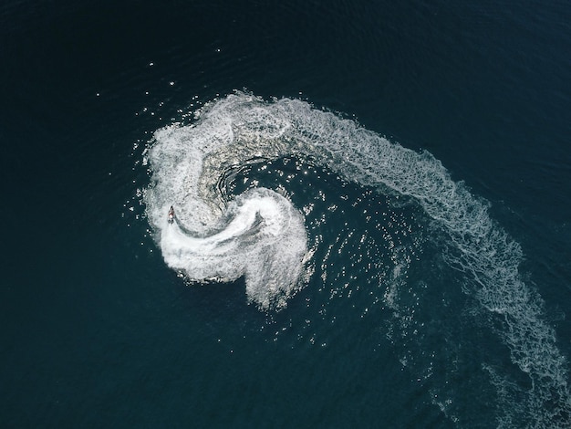 Vista aerea dall'alto verso il basso della traccia di schiuma d'acqua con una bella sfumatura blu intenso dell'oceano bellissimo sentiero bianco