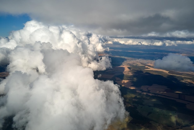 Vista aerea dalla finestra di un aereo ad alta quota della terra coperta da nuvole bianche gonfie cumulus