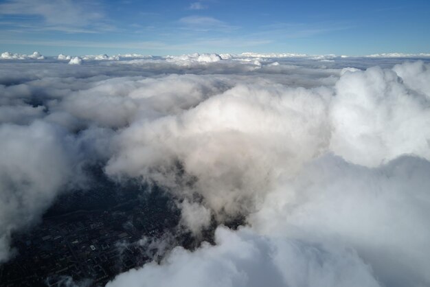 Vista aerea dalla finestra di un aereo ad alta quota della terra coperta da nuvole cumulus gonfie che si formano prima di una tempesta di pioggia