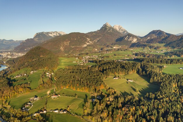 Vista aerea dei prati verdi con i villaggi e la foresta in montagne austriache delle alpi.