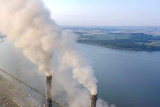 Vista aerea dei tubi alti della centrale elettrica del carbone con fumo nero che si alza atmosfera inquinante all'alba.