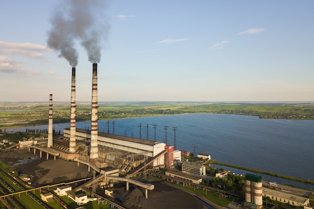 Vista aerea dei tubi alti della centrale elettrica del carbone con fumo nero che si alza atmosfera inquinante.