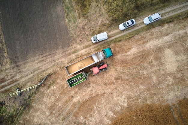 Vista aerea del camion del carico che guida su strada sterrata tra i campi di grano agricoli che producono molta polvere. Trasporto del grano dopo essere stato raccolto dalla mietitrebbia durante la stagione di raccolta.