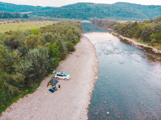 Vista aerea del campeggio in auto vicino al fiume di montagna