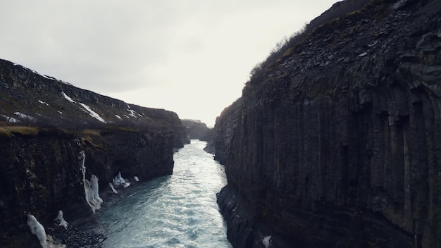 Vista aerea del canyon della cascata di Gullfoss, maestoso paesaggio nordico con ruscelli d'acqua e massicce colline ghiacciate. Spettacolare cascata in Islanda che scorre giù dalle scogliere. Slow motion.