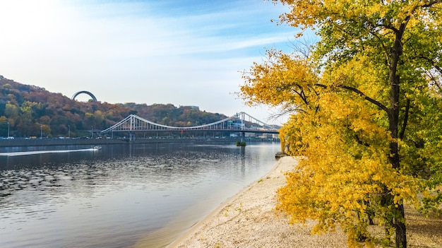 Vista aerea del drone del ponte pedonale del parco autunnale, alberi gialli di caduta, isola di Truhaniv, fiume Dnepr e paesaggio urbano di Kiev dall'alto, città di Kiev, Ucraina