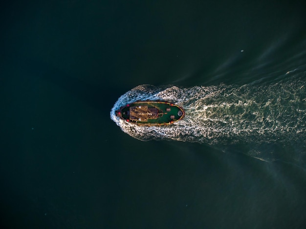 Vista aerea del drone del rimorchiatore industriale che assiste la barca in acque profonde