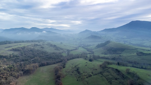 Vista aerea del drone della strada di montagna e dei prati verdi in una giornata nuvolosa con nebbia