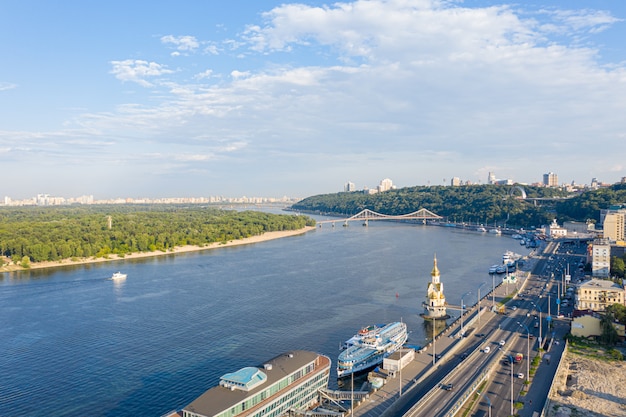 Vista aerea del fiume Dnieper, delle colline di Kiev e della città di Kiev vicino al ponte pedonale, Ucraina. Città di notte, crepuscolo, retroilluminazione