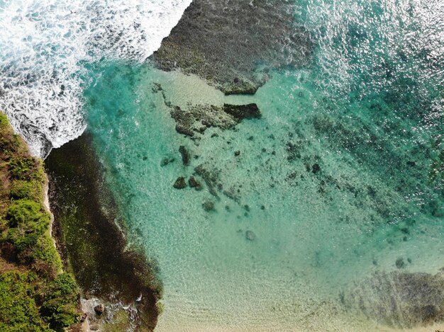 Vista aerea del mare blu con scogliera di roccia sulla costa sabbiosa di Bali