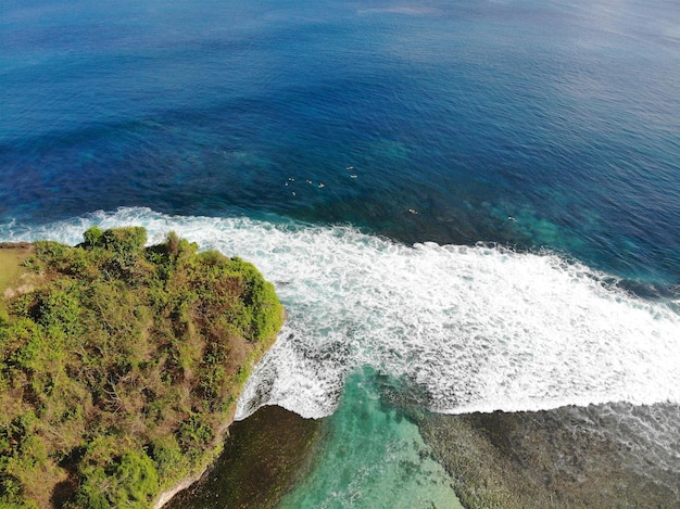 Vista aerea del mare blu con scogliera di roccia sulla costa sabbiosa di Bali