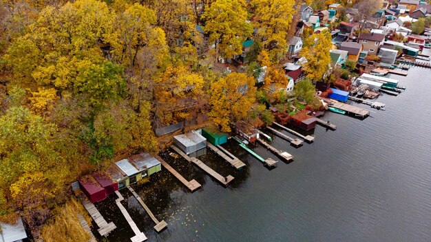 Vista aerea del paesaggio autunnale del villaggio sulle rive del fiume con passerelle per barche