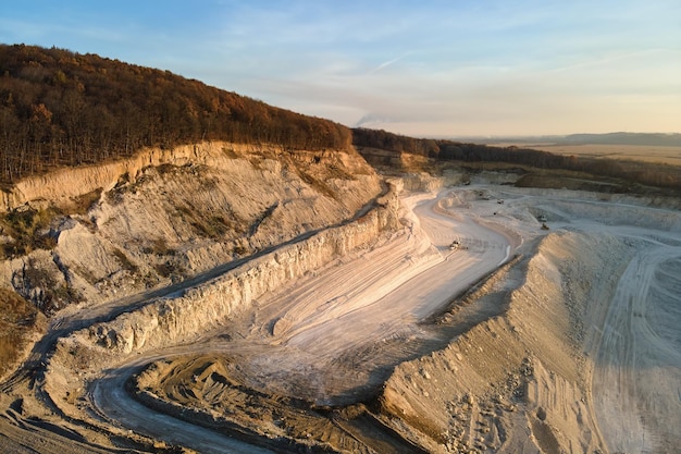 Vista aerea del sito minerario a cielo aperto di materiali calcarei per l'industria delle costruzioni con escavatori e autocarri con cassone ribaltabile