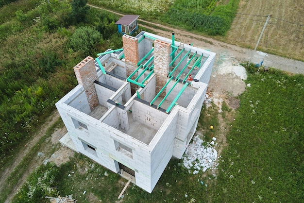Vista aerea del telaio incompiuto della casa privata con pareti in calcestruzzo leggero aerato e travi in legno del tetto in costruzione.