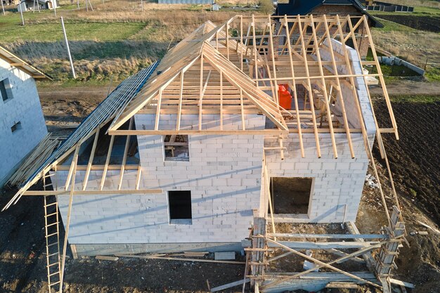 Vista aerea del telaio incompiuto di una casa privata con pareti in calcestruzzo leggero aerato e struttura del tetto in legno in costruzione.