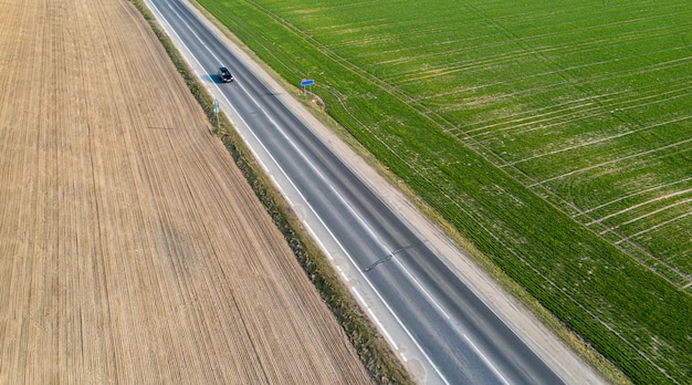 Vista aerea del traffico su strada a due corsie attraverso la campagna e campi coltivati