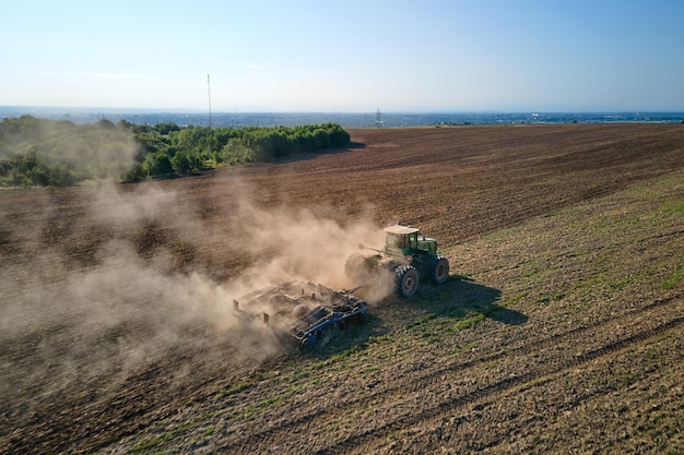 Vista aerea del trattore che ara il campo agricolo della fattoria che prepara il terreno per la semina in estate